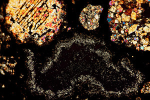 Traliechondrule en twee porfirische chondrules samen met een CAI in de koolstofhoudende chondriet Allende. Werkelijke afmetingen van het beeldveld zijn 2,25 mm bij 1,5 mm. (Foto: Zenit/Gert Jan Netjes)